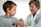 A young boy is receiving a vaccination from a smiling healthcare professional. The boy is looking away, while the healthcare worker gently administers the injection. Both are indoors with a plain background, suggesting a clinical setting.