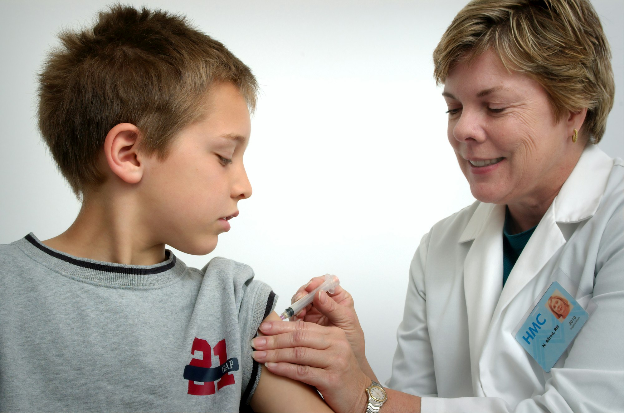 The nurse depicted in this 2006 photograph was in the process of administering an intramuscular vaccination in the left shoulder of a young boy. The nurse was pinching the overlying shoulder skin, in order to immobilize the injection site.