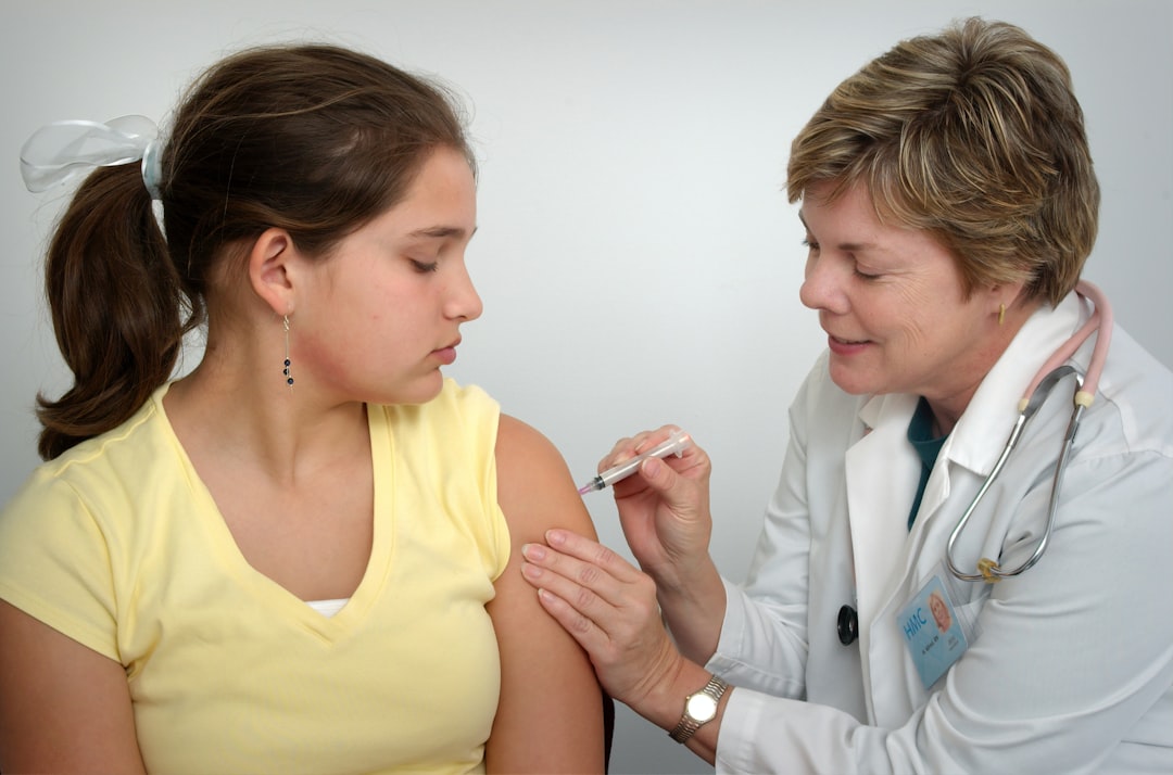 The nurse depicted in this 2006 photograph, was in the process of administering an intramuscular vaccination in the left shoulder of a young girl. The nurse was pinching the overlying shoulder skin, in order to immobilize the injection site.