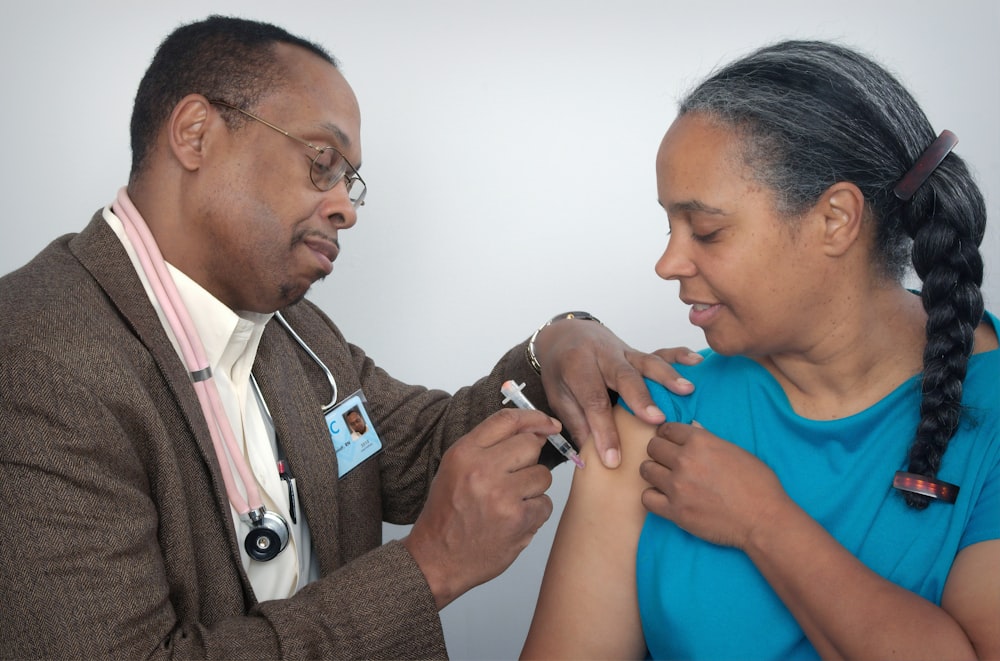 man doing syringe on woman wearing blue shirt
