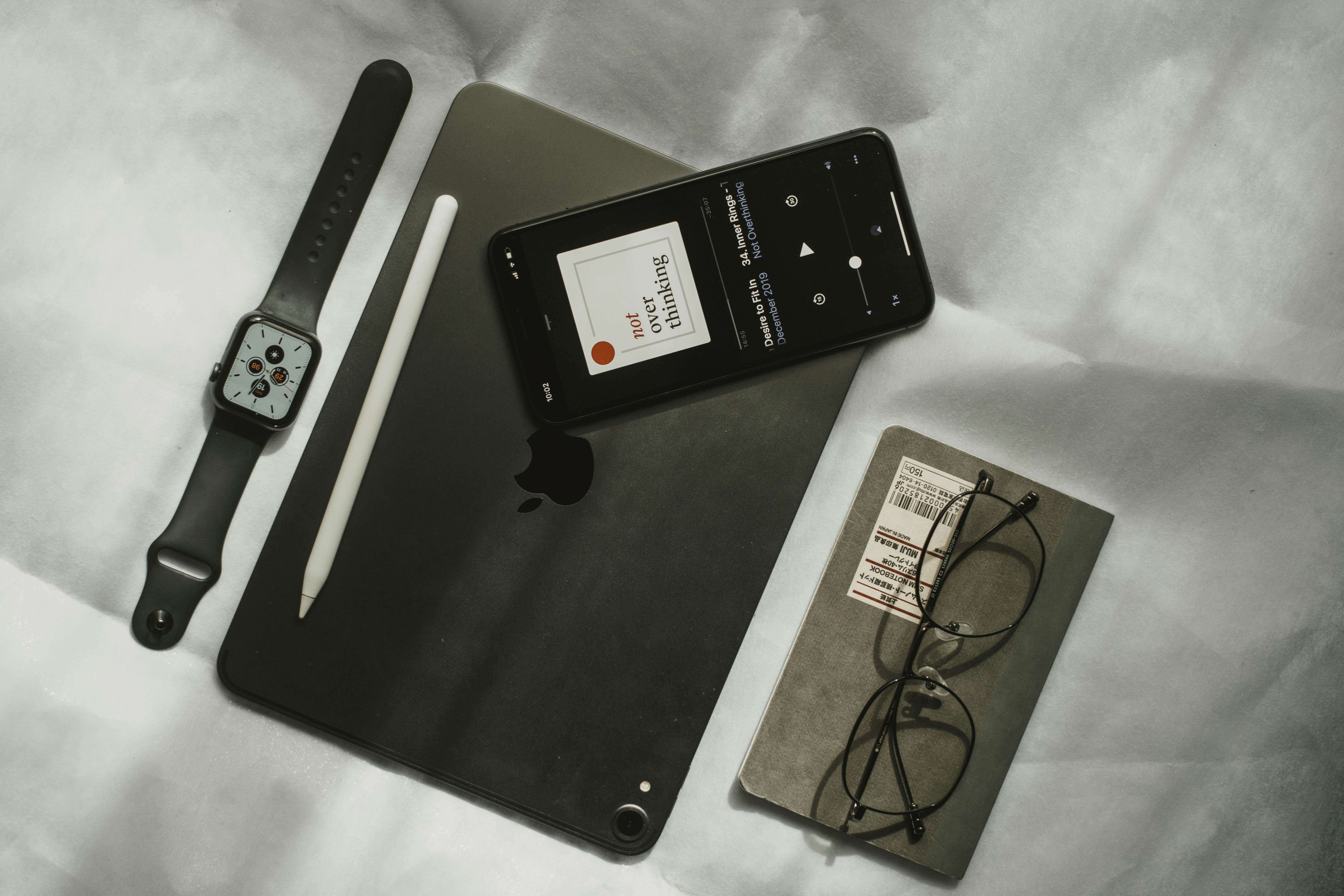 black iPhone and iWatch with eyeglasses