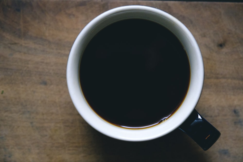 caneca de cerâmica branca e preta preenchida com líquido preto