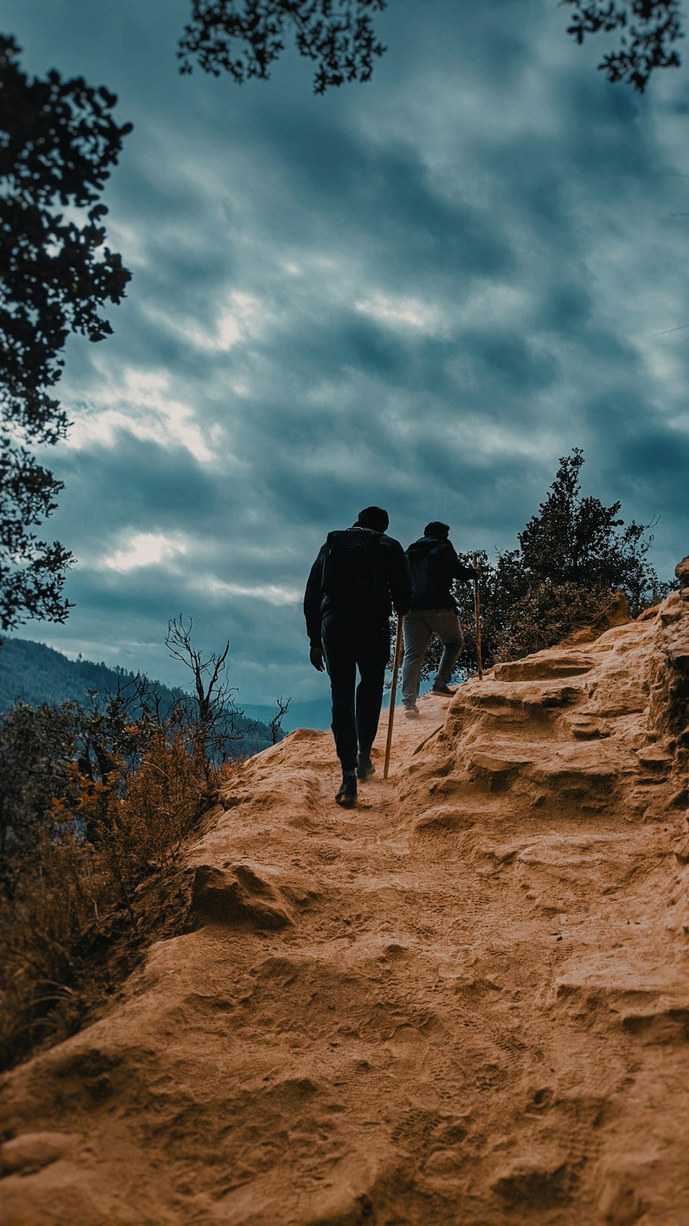 two men hiking on rocky field during day