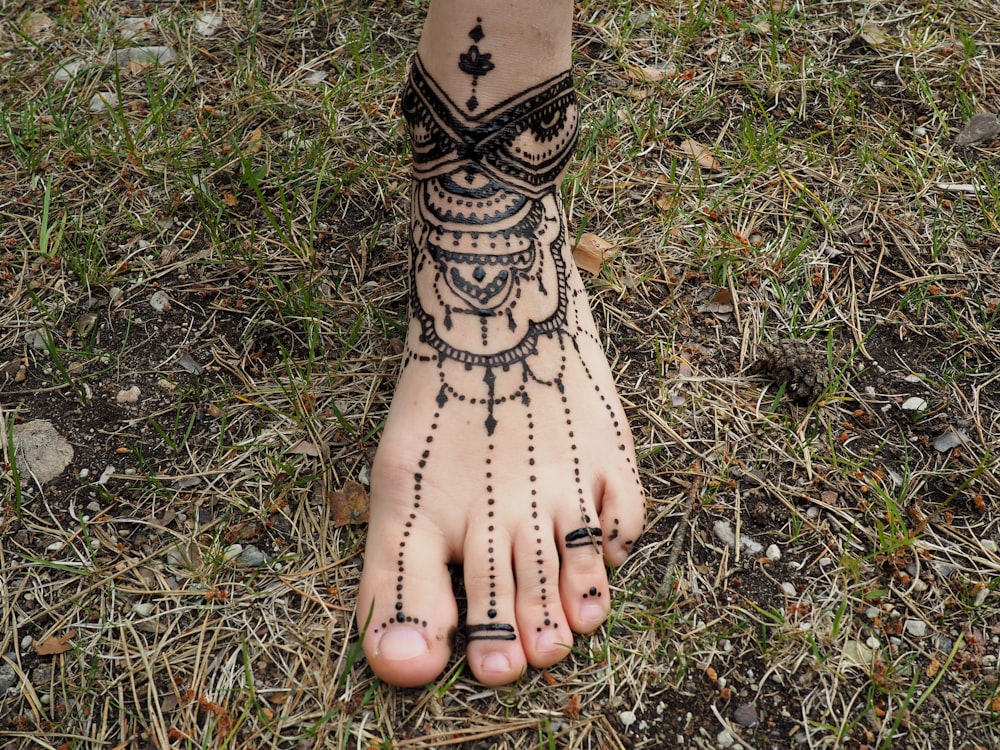 personne pieds nus avec tatouage mehndi sur le pied gauche