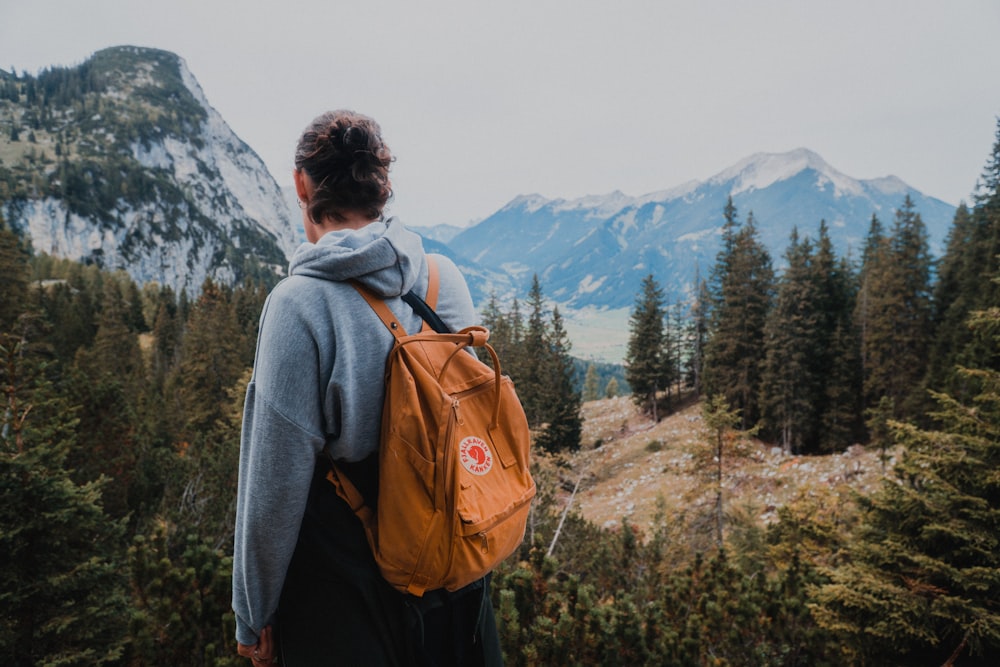 woman wearing backpack near trees during day