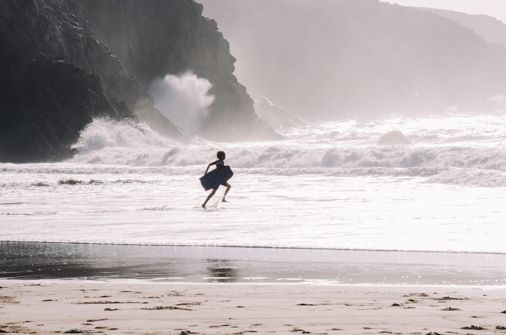silhouette of person carrying bodyboard on seashore