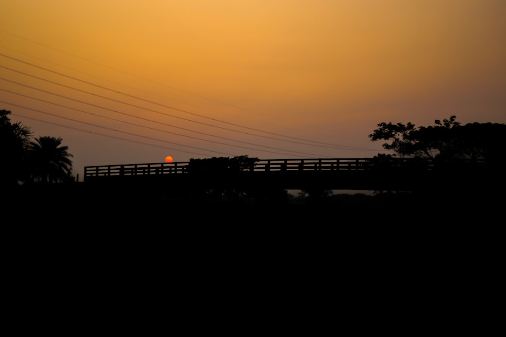 the sun is setting over a bridge with power lines