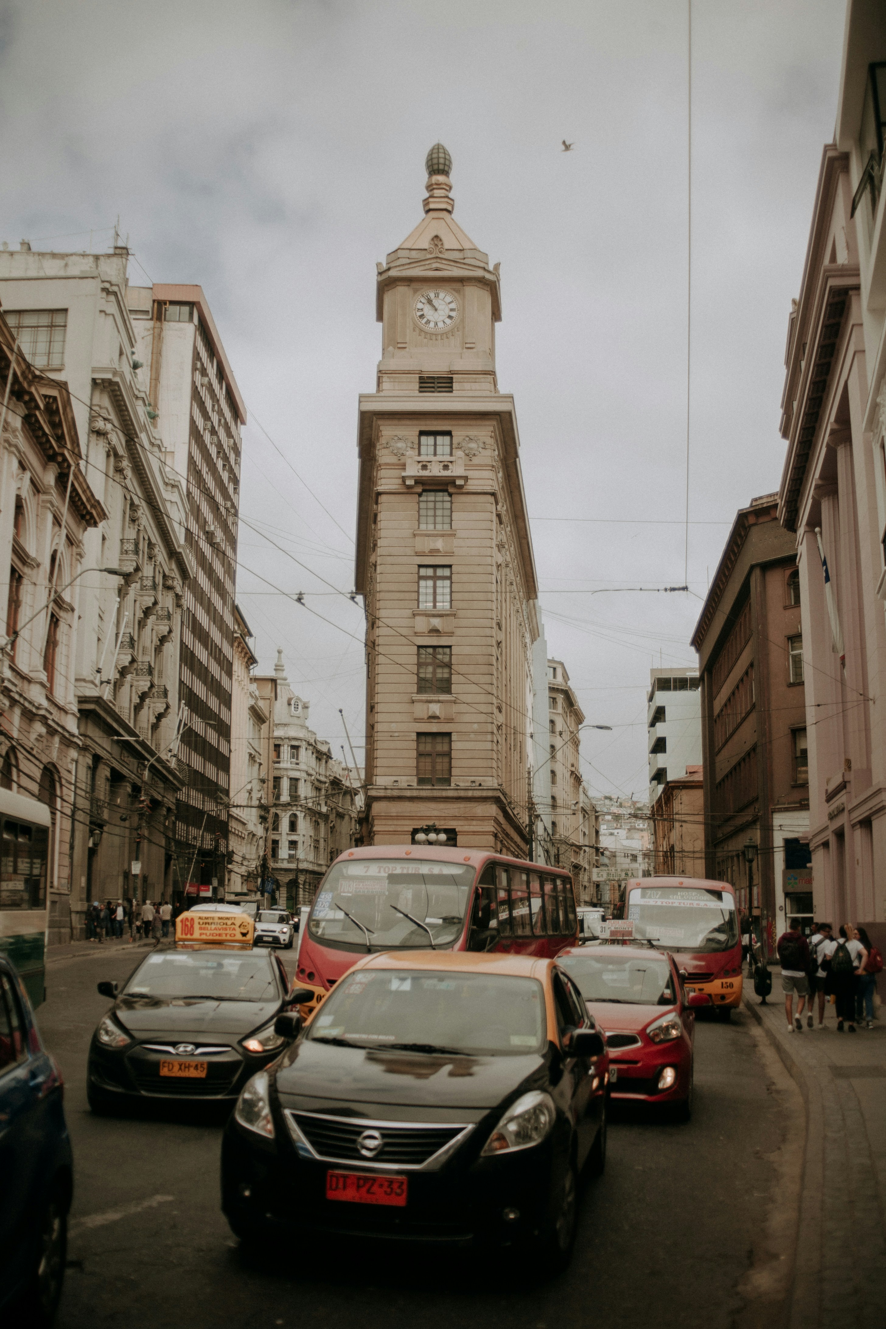 pessoas andando no caminho perto de edifícios e diferentes veículos na estrada durante o dia