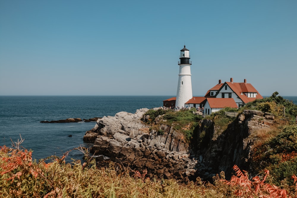 lighthouse beside house on island during day