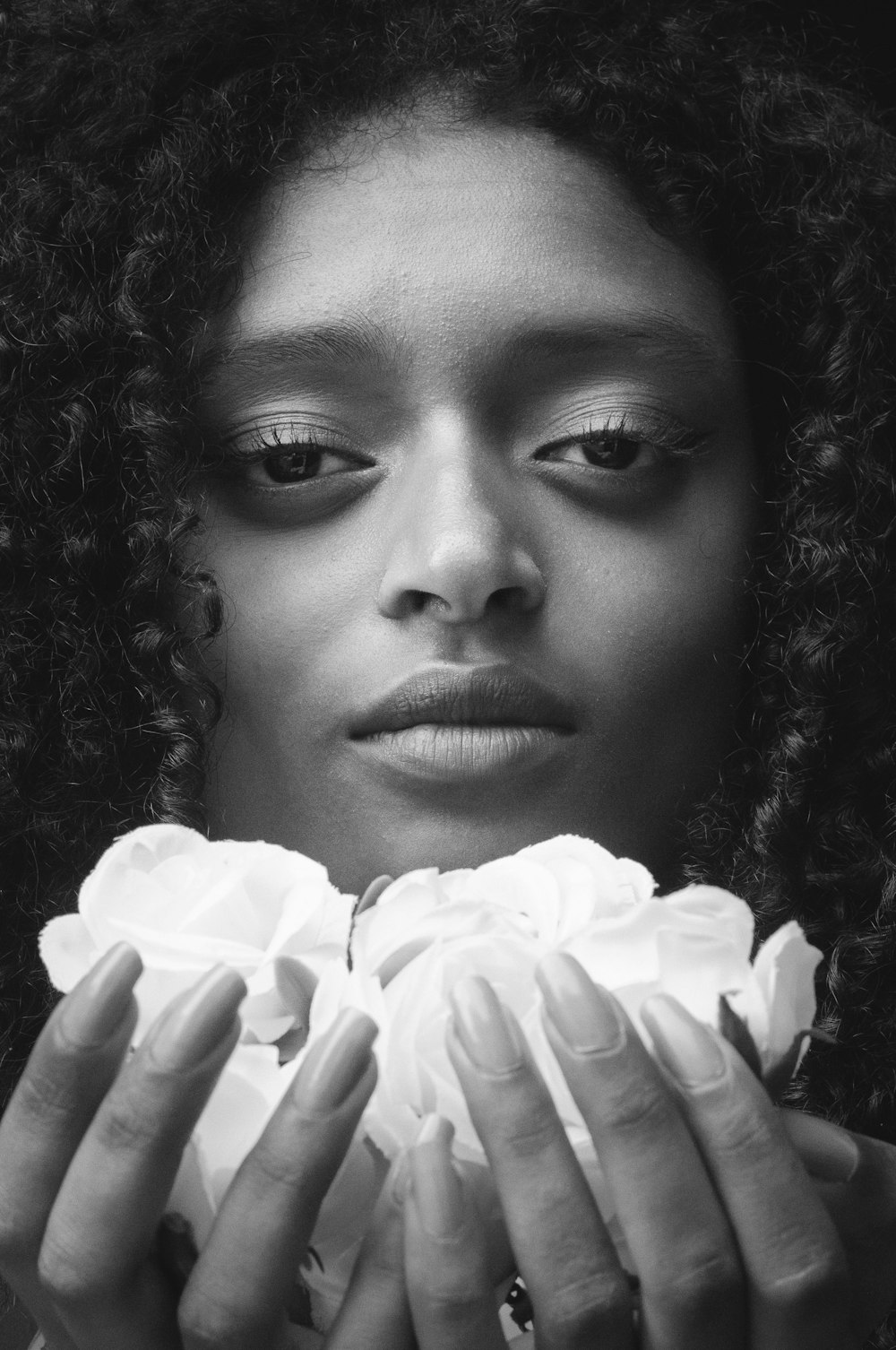 grayscale photography of woman holding petaled flower
