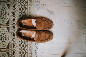 Casual men’s loafers in rich brown suede resting on a textured concrete floor.