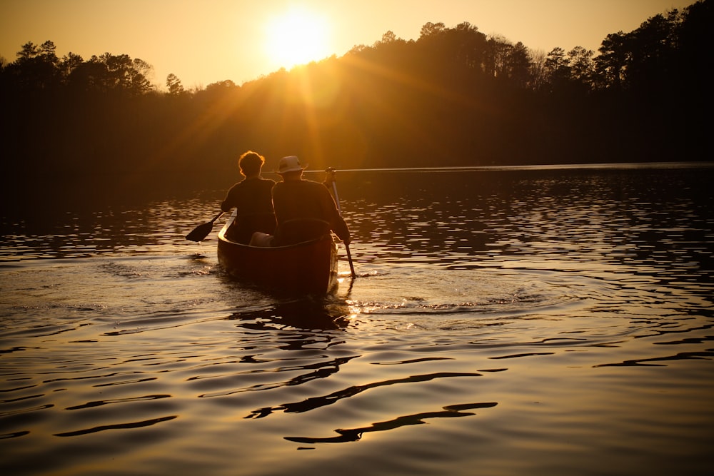hommes ramant bateau pendant le coucher du soleil
