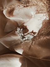 Close-up of delicate hypoallergenic flower earrings resting on soft linen fabric.