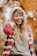 Photo of a smiling woman wearing a soft knit sweater outdoors in autumn.