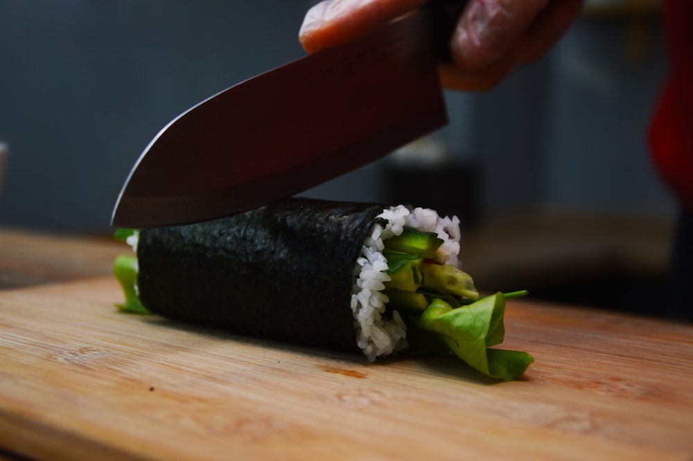 Foto mit flachem Fokus einer Person, die Sushi schneidet