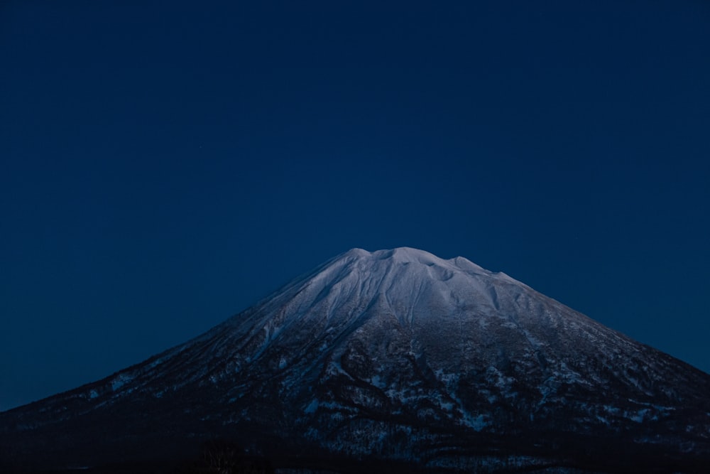 uma montanha coberta de neve à noite com a lua no céu