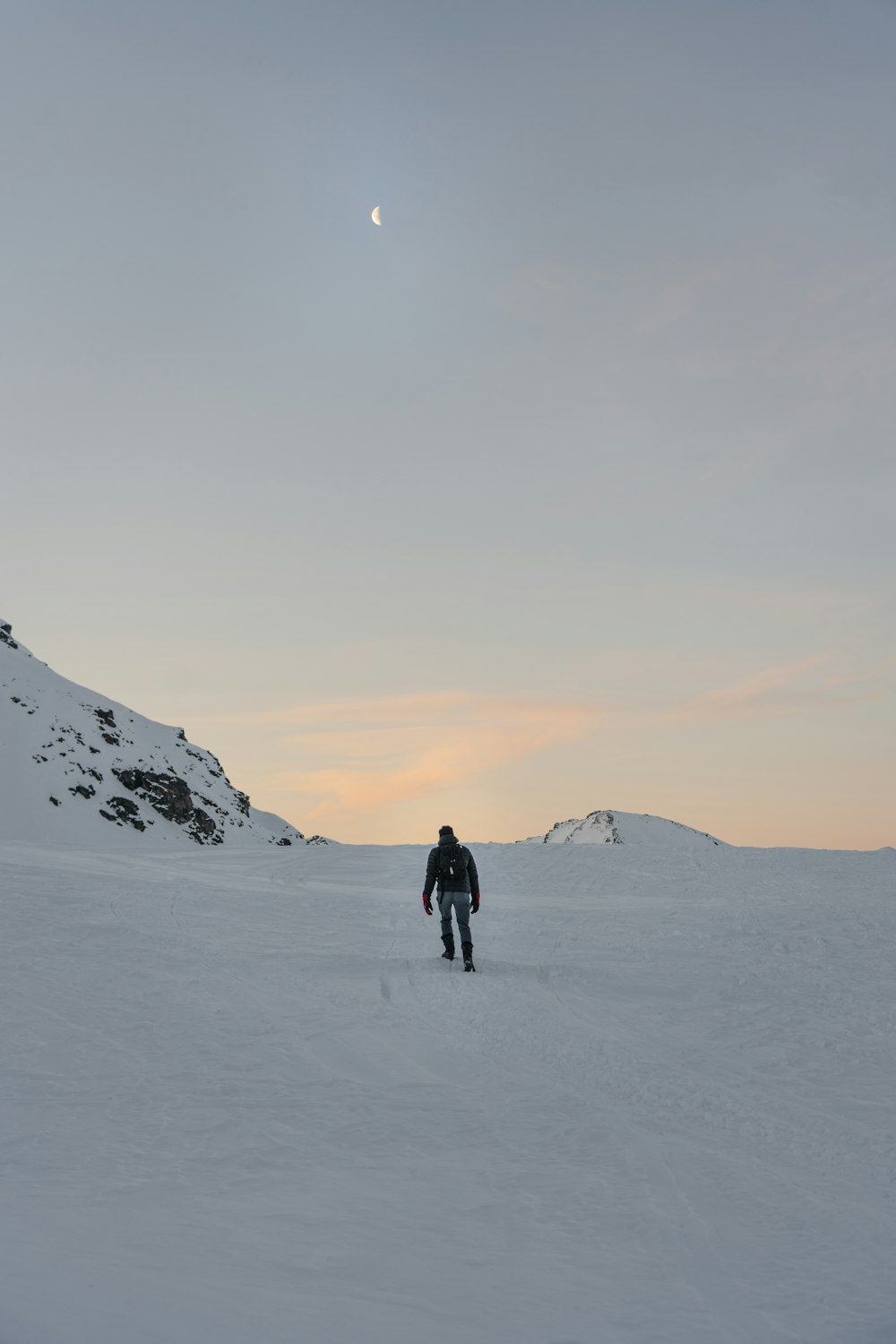 person walking on snow-covered field and mountain during daytime