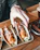 Close-up shot of a hand reaching for a crispy dried fish snack next to a cold beer glass.