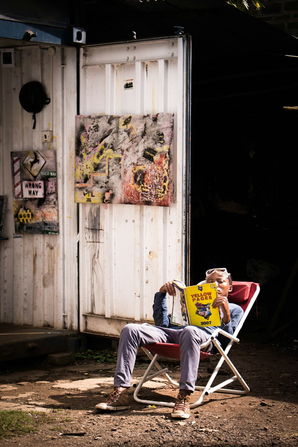 man sitting on folding chair reading book