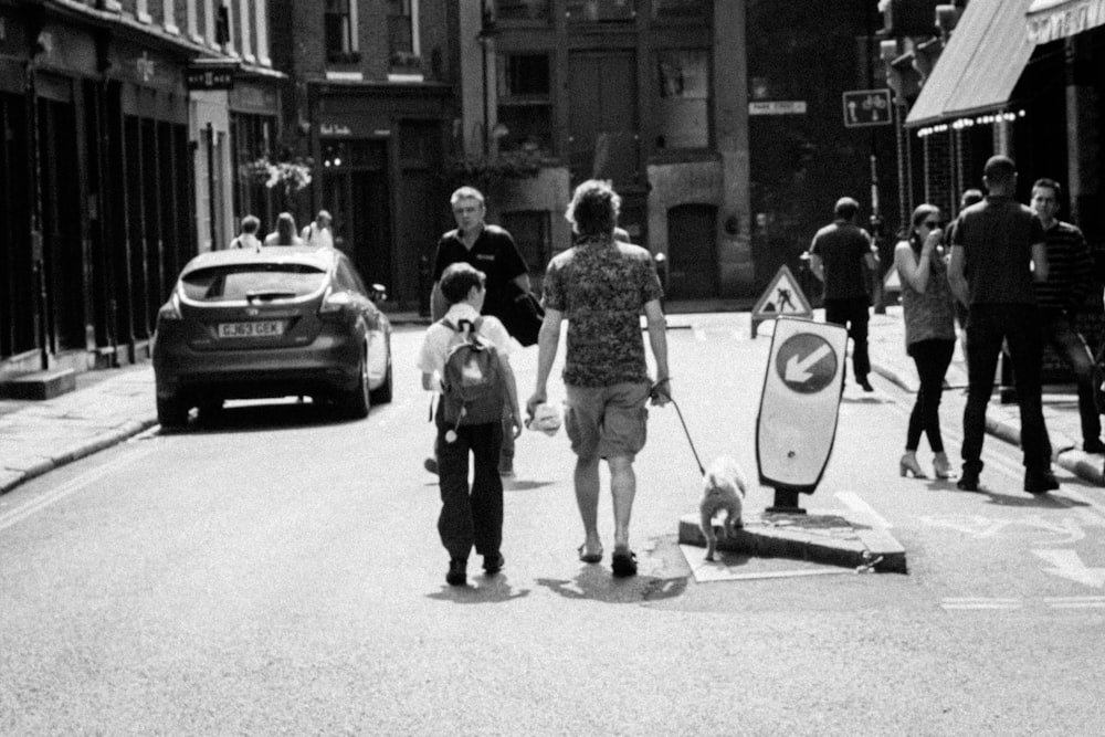 grayscale photo of people walking near park vehicle