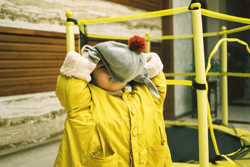 baby wearing yellow jacket and gray bennies