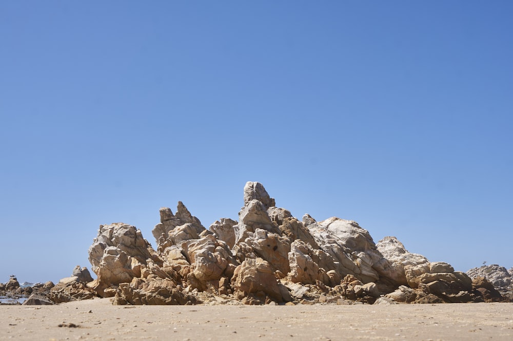 a large pile of rocks sitting on top of a sandy beach