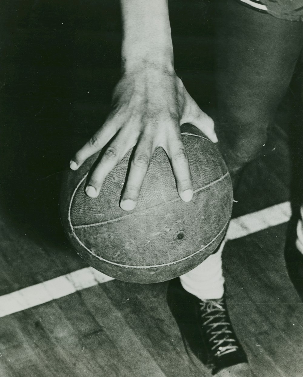 une personne tenant un ballon de basketball sur un plancher de bois franc