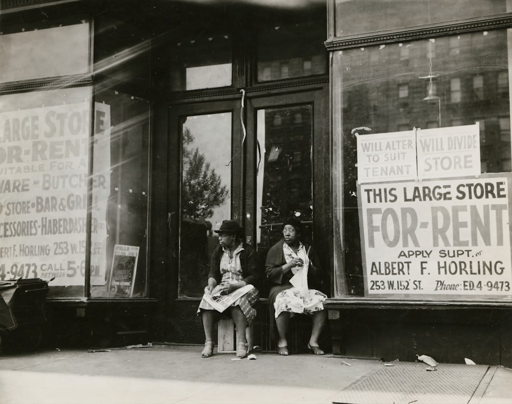 Photo en niveaux de gris de personnes assises dans la rue