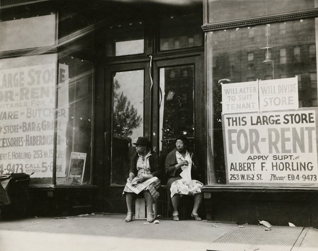 Sidewalk sitters. Two women sitting in doorway of empty storefront that is being offered for rent, Harlem, New York City, ca. 1930s