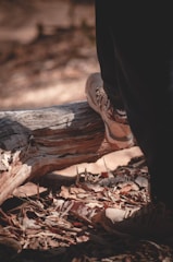 A pair of sturdy hiking boots on a trail covered with autumn leaves.