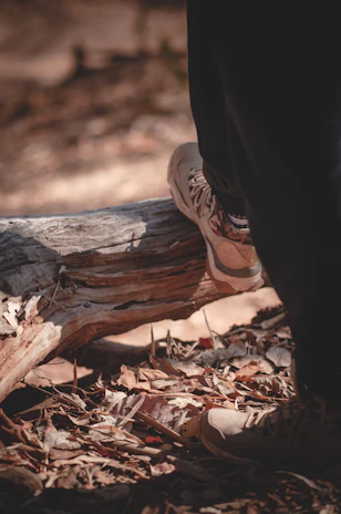 Close-up of hiking boots on a forest trail covered with autumn leaves.