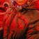 A person wearing a heavily padded, dark puffer jacket with a hood. The jacket has a zipper in the front and features a subtle embroidered logo on one sleeve. The person is also wearing a scarf and is standing outdoors, where a vehicle is partially visible in the background.