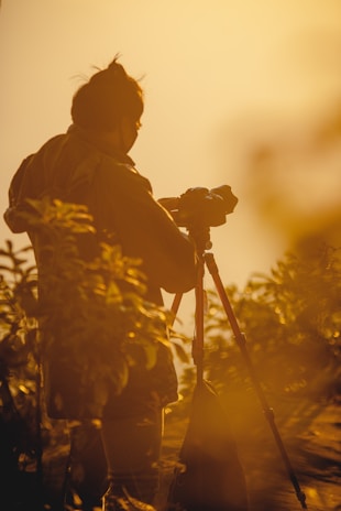 A photographer setting up a camera outside a bright Southern California home during golden hour.