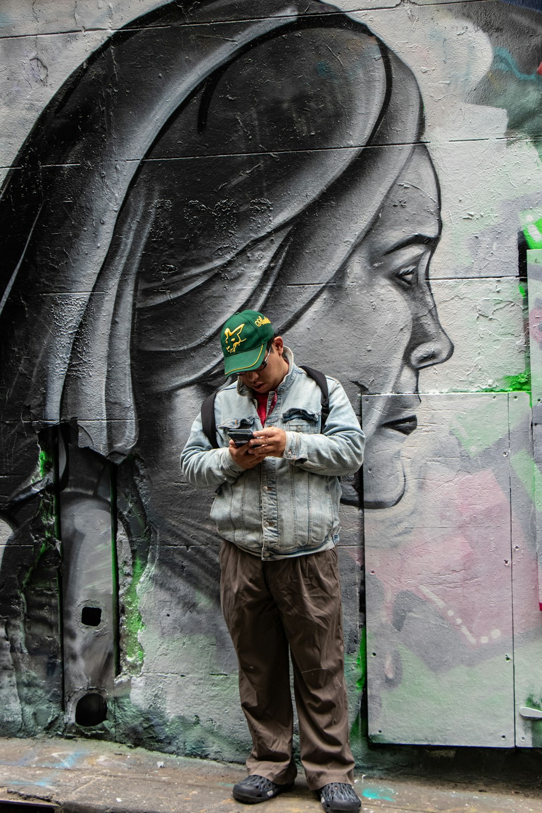 man wearing grey jacket and brown pants using smartphone