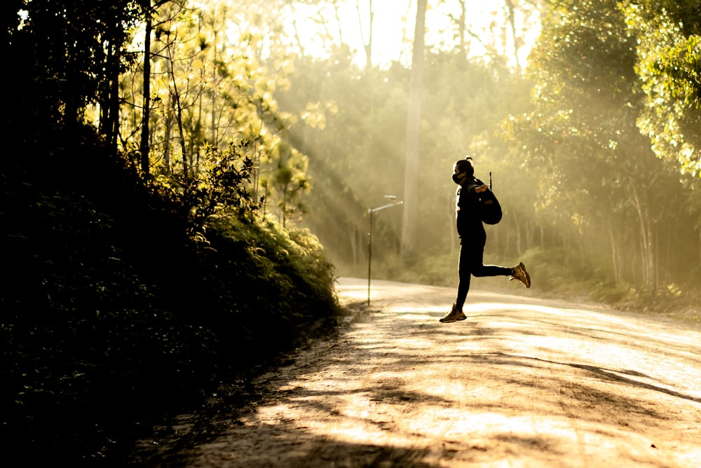 jumping man carrying backpack beside tree