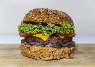 A delicious burger on a wooden table with fresh ingredients.