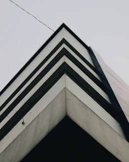 Minimalist architectural corner with sharp lines against a bone-colored backdrop.