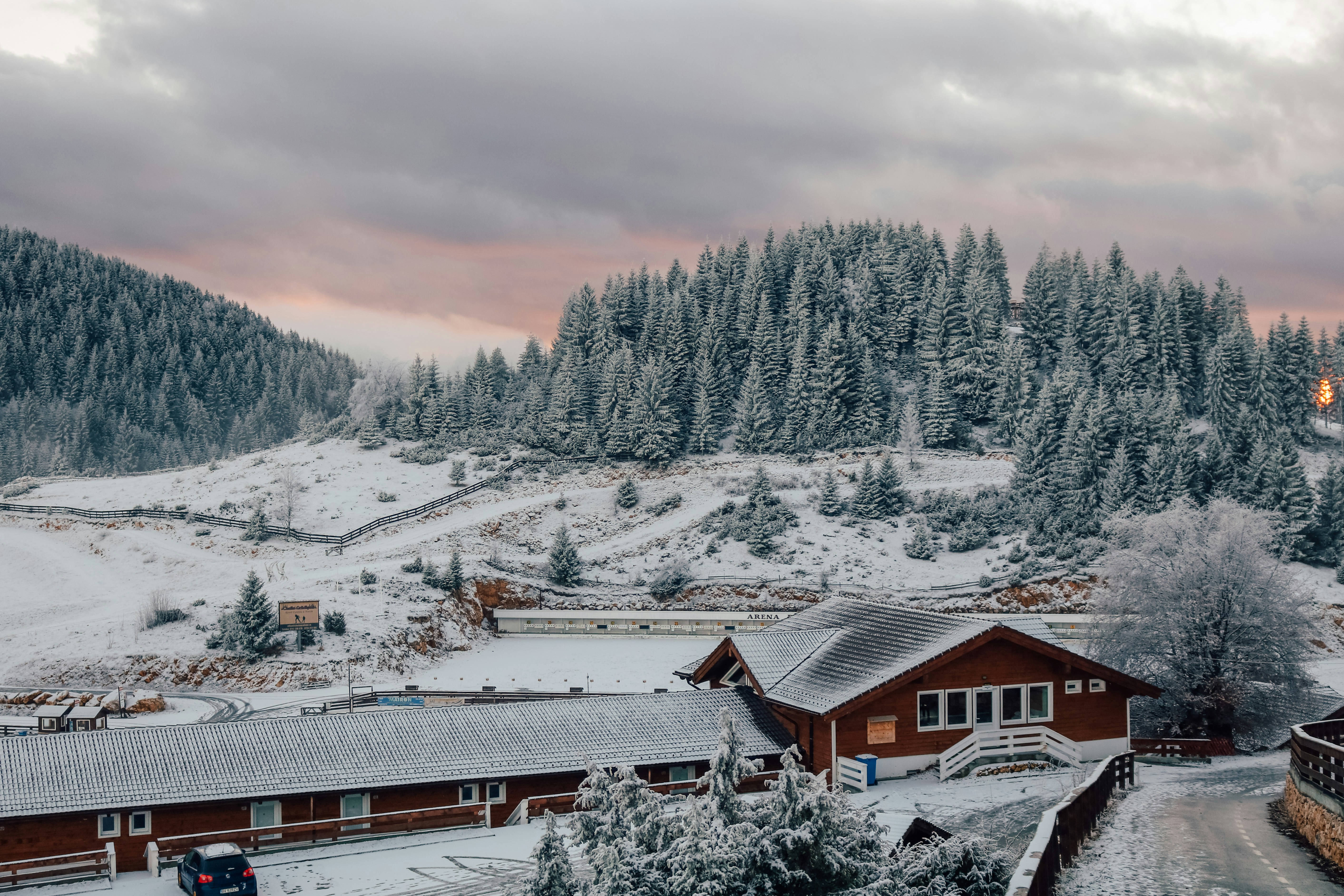 brown building near snow covered trees under cloudy sky