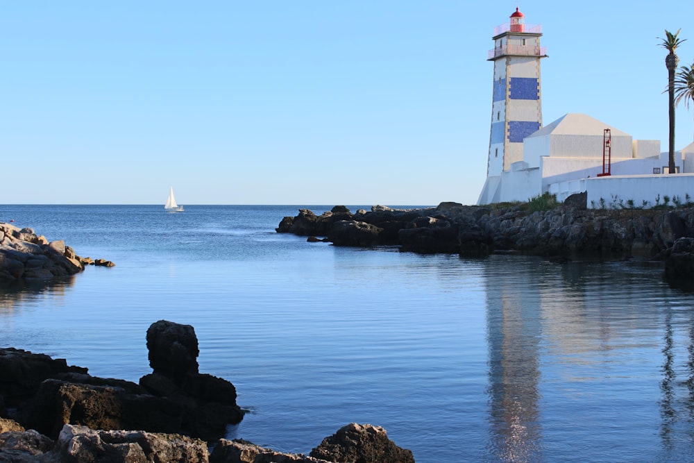 white and blue lighthouse beside calm body of water during daytime