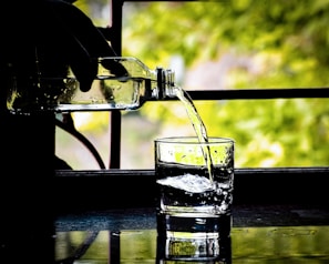 A transparent bottle being used to pour liquid into a glass.