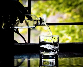 A transparent bottle being used to pour liquid into a glass.