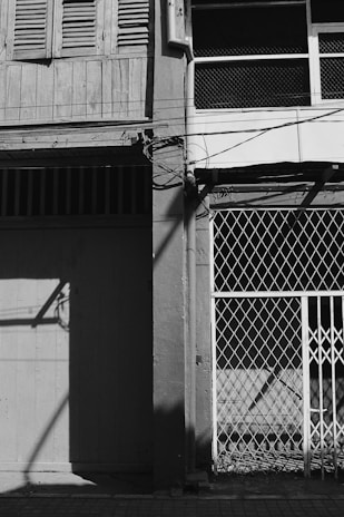 A black and white photograph capturing a quiet, forgotten urban corner in Brest, with subtle textures of peeling paint and shadows.