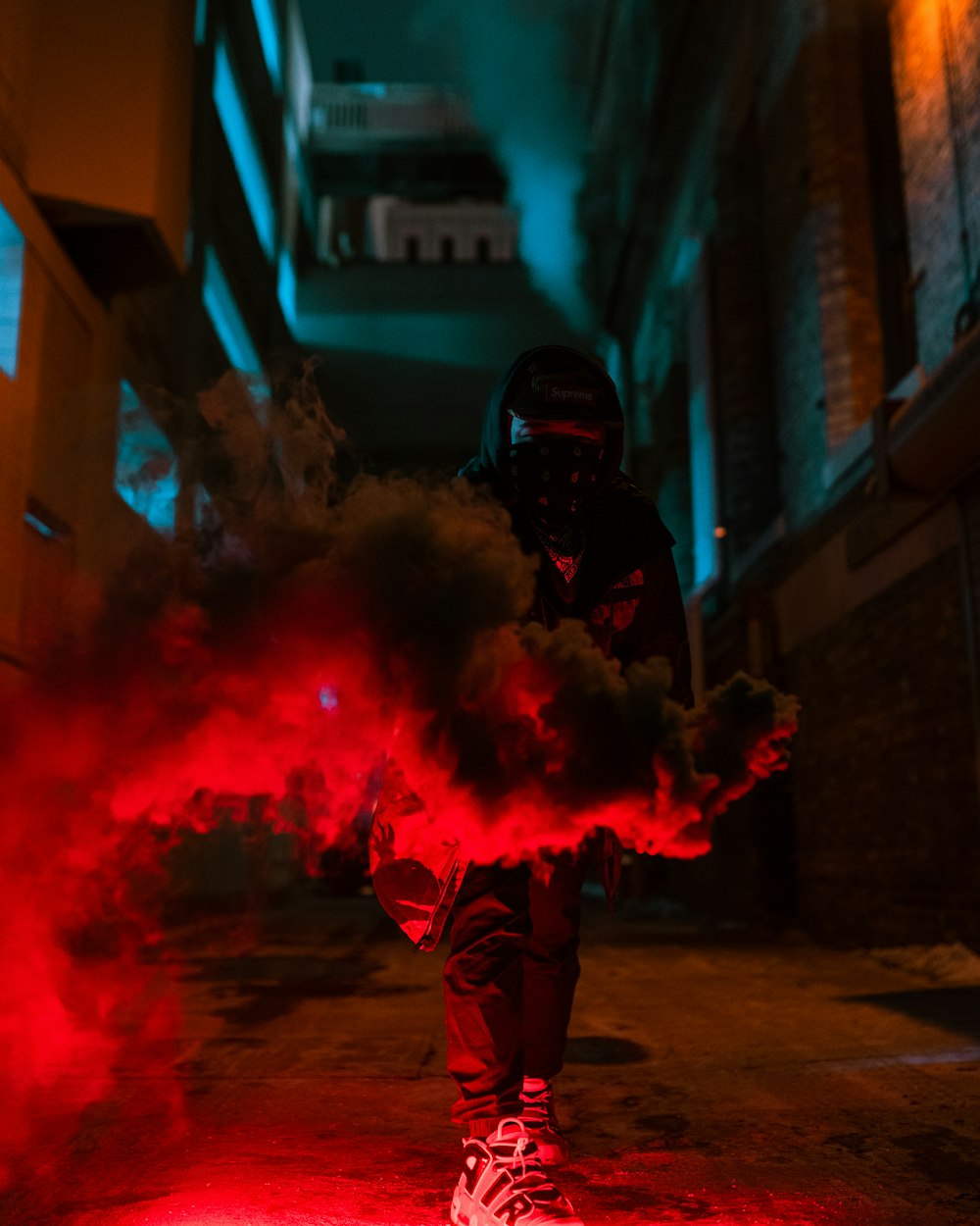 a person in a dark alley with red smoke coming out of their feet