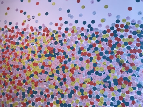 A vibrant wall covered with various sizes and shapes of personalized stickers.