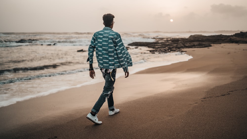 uomo che cammina lungo la riva del mare durante il giorno