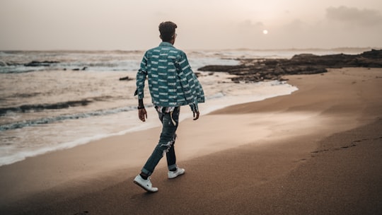 man walking along the seashore during daytime in Diu India