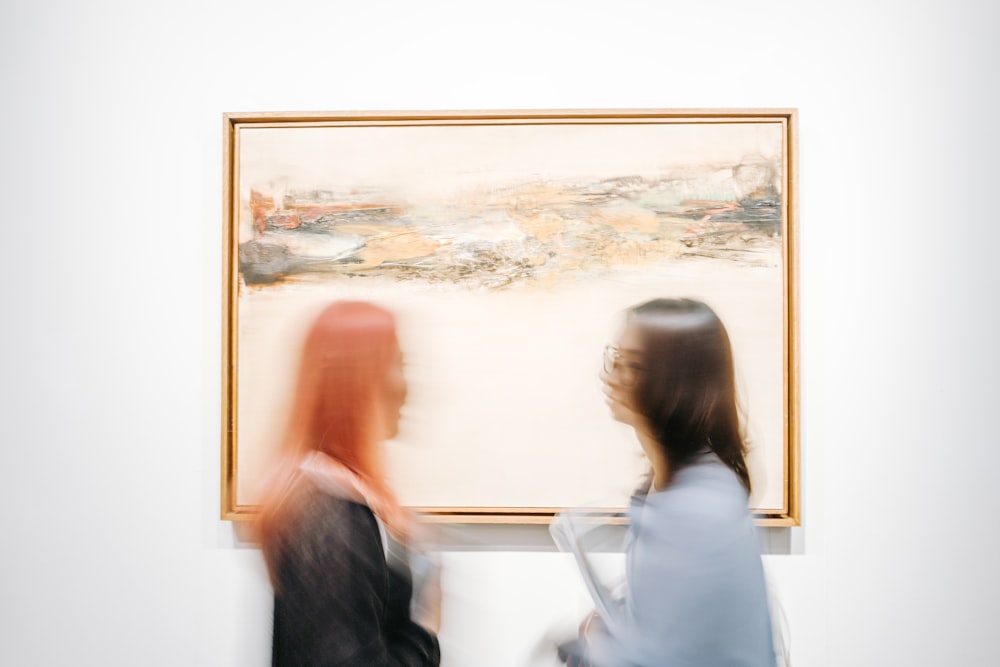 two women standing beside painting