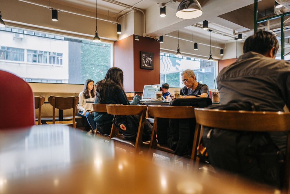 Personas sentadas a la mesa mientras usan computadoras portátiles