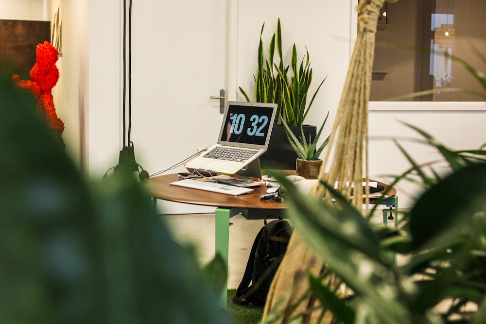 MacBook Air displaying 10:32 time on round brown wooden table