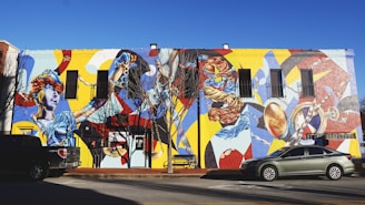 gray and black cars parked beside building with graffiti